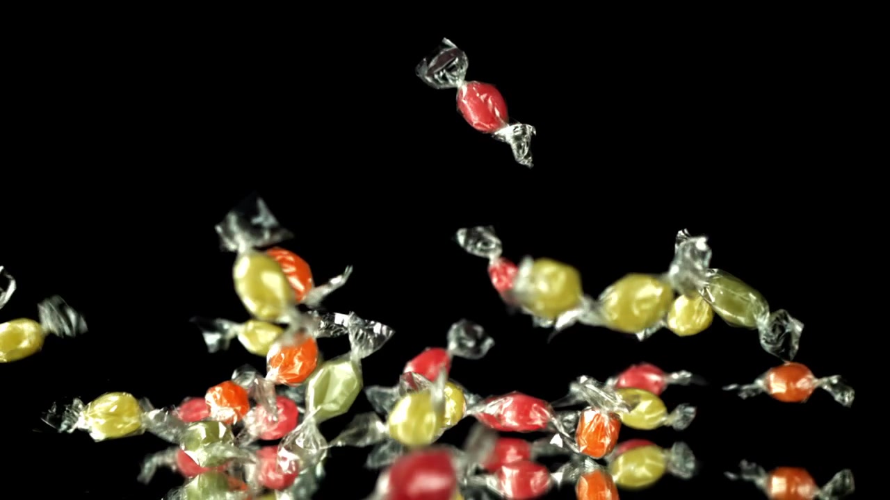 Doces Coloridos Caindo em Câmera Lenta em Fundo Preto