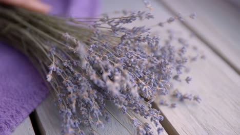 Female-hand-puts-a-bouquet-of-lavender-on-a-wooden-table