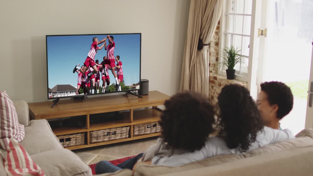 Famiglia felice seduta a casa insieme che guarda una partita di calcio in TV