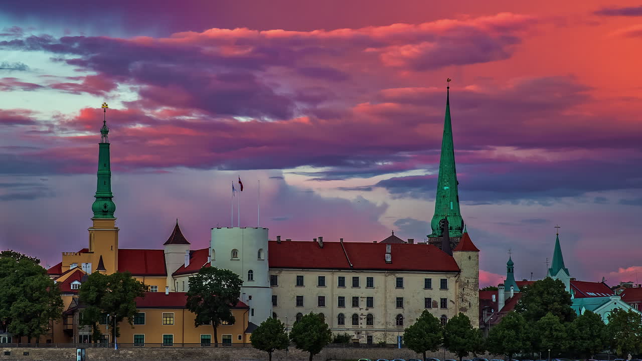 hermosa vista del casco antiguo de riga, letonia con bandera letona soplando por la catedral de cúpula y nubes pasando en timelapse