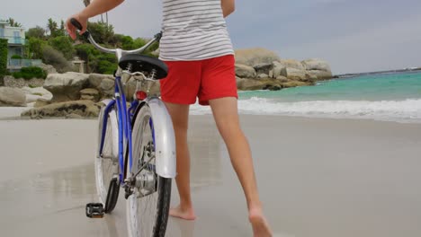 rear view of caucasian man walking with bicycle on the beach 4k