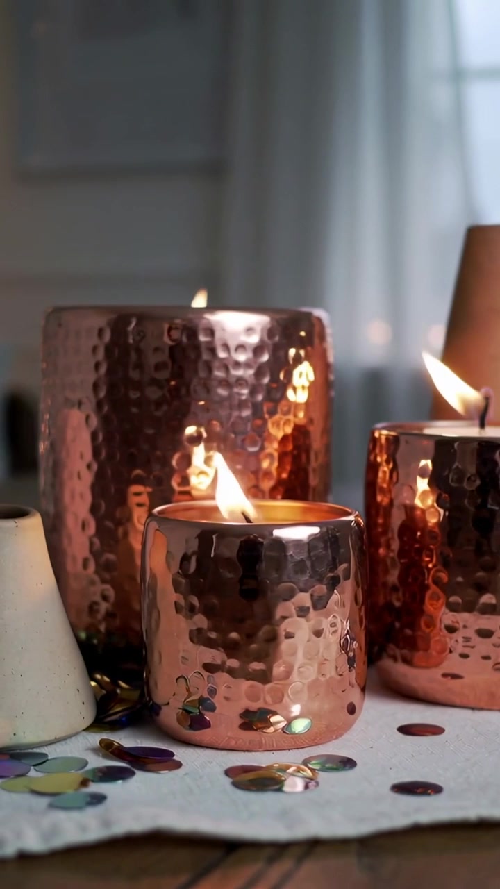 Video verticale: Trio di candele in bronzo martellato tremolanti dopo l'accensione su un panno vicino alla finestra.