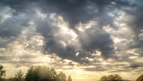 Lapso-De-Tiempo-Del-Amanecer-Con-Nubes-Pesadas-En-Movimiento-Y-Rayos-De-Luz-Dorados-Que-Se-Abren-Paso