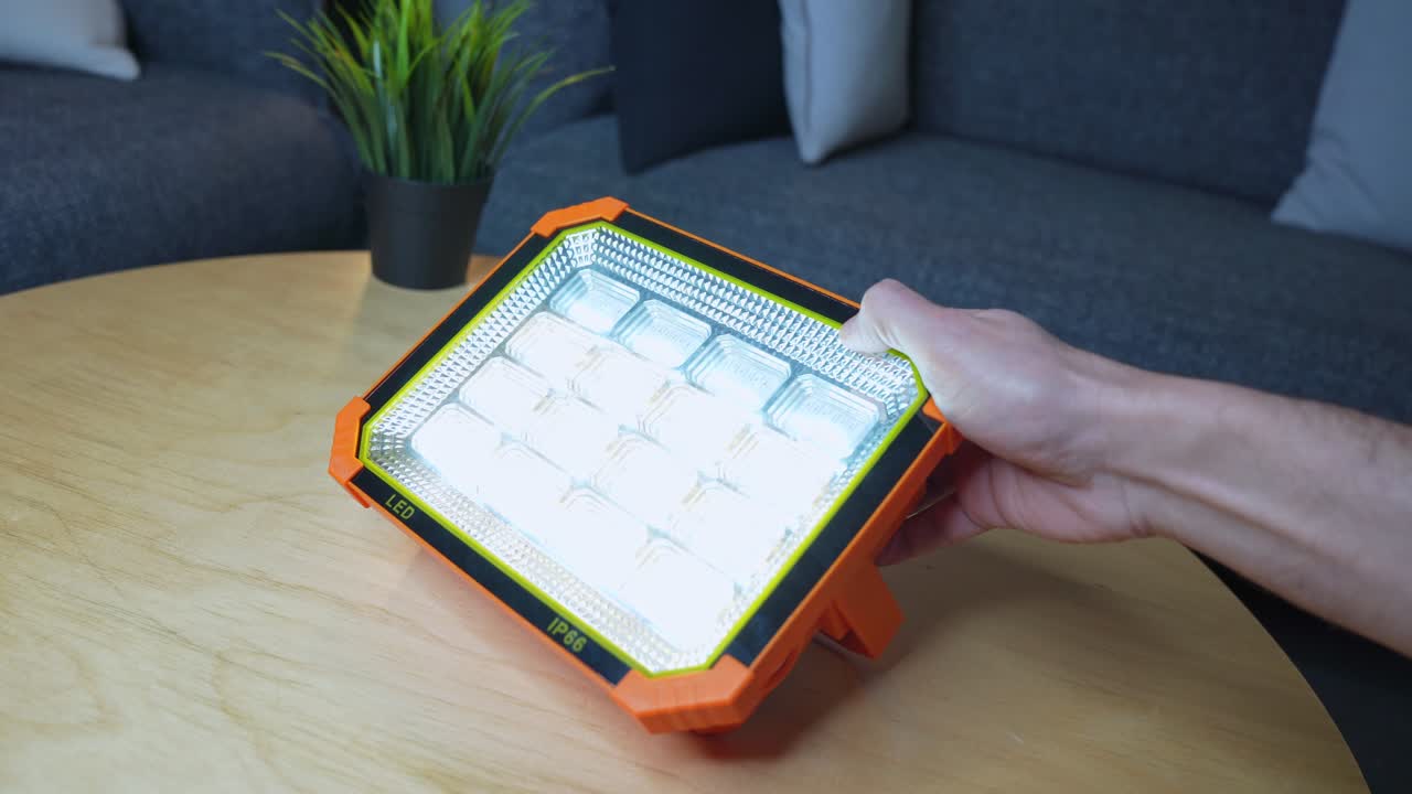 High-quality clip of a person testing an ultra-bright LED floodlight on a table—ideal for tech, product demos, or lighting concepts.