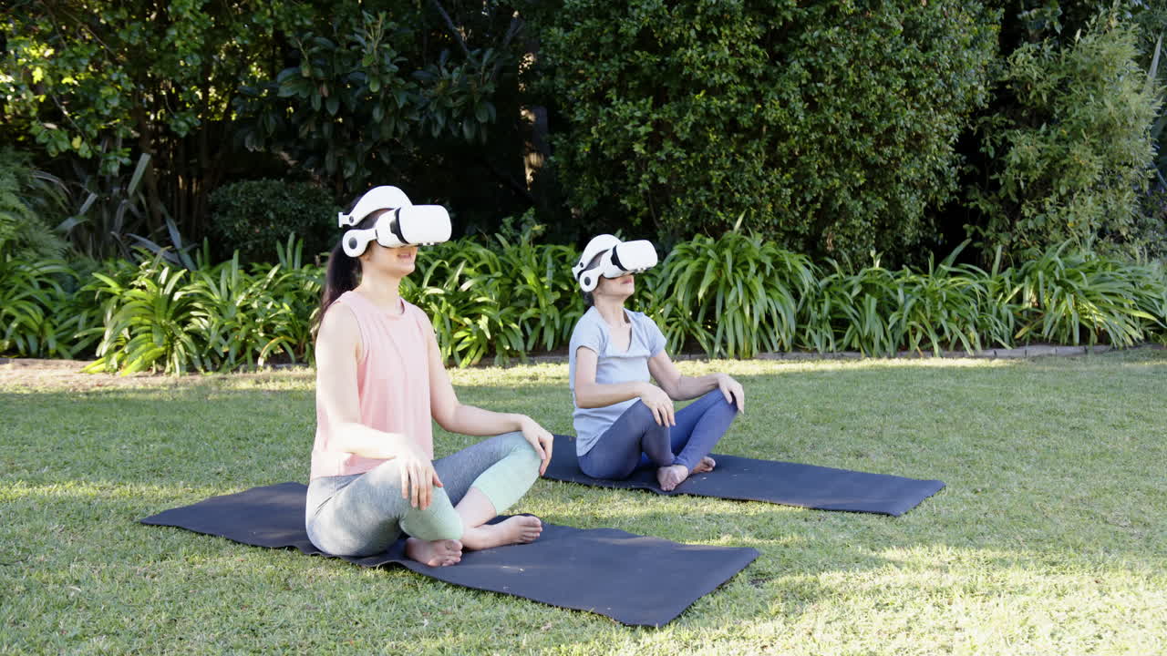 In garden, Asian grandmother and granddaughter practicing yoga using VR headsets