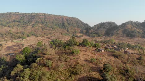 low drone shot over a rural indian farming village out towards their farmlands