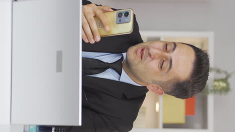 Vertical-video-of-Home-office-worker-man-talking-on-the-phone-facetime-happily.