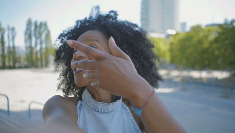 woman having video chat on phone outside, waving hand, talking