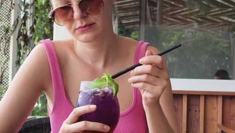 una mujer disfrutando de un cóctel púrpura.