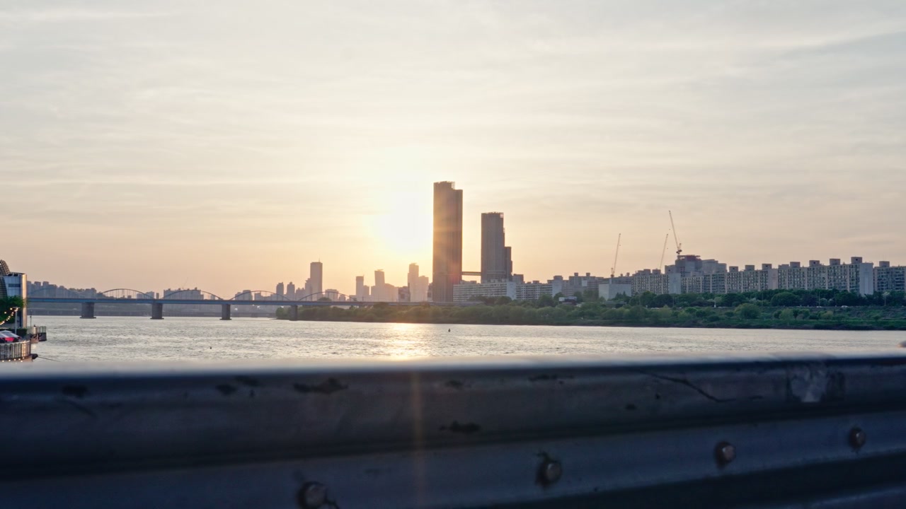 O Parque Hangang, ao longo do Rio Han, oferece vistas vibrantes da orla, horizontes urbanos e a Ponte Banpo, onde os moradores se reúnem para relaxar, passear e apreciar os pores do sol da hora dourada. Este é um pôr do sol de pico da primavera.