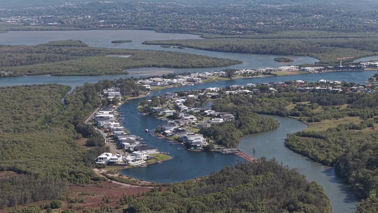 Casas à beira do Rio Coomera Cercadas por Mangues Verdes. Queensland, Austrália. Tomada aérea em órbita.