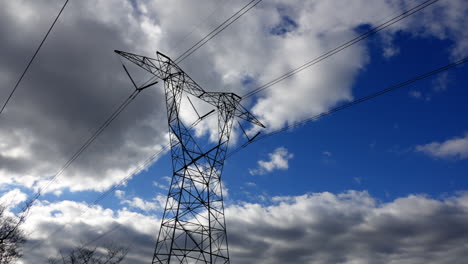 Electrical-pylon-and-transmission-lines-with-clouds-moving-rapidly-in-a-blue-sky