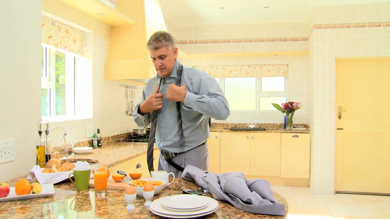 hombre en la cocina apresuradamente poniendo corbata