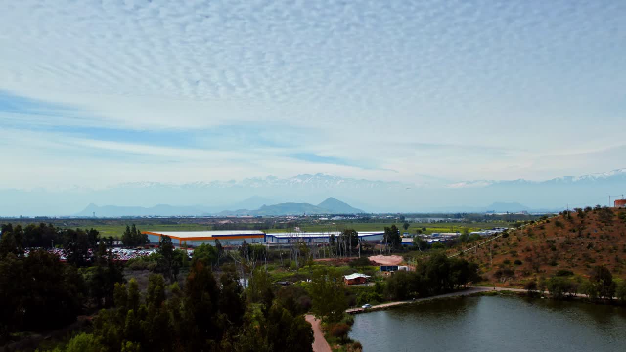 Aerial view dolly out establishing of the Andes mountain range with a commercial airliner taking off and a sky with clouds in patterns, Santiago, Chile