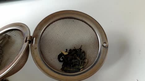 stainless steal filter tea ball being filled of loose green tea
