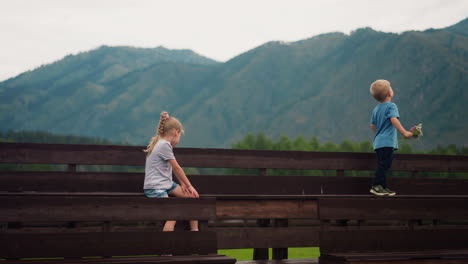 Niño-Con-Flores-Silvestres-Mira-Montañas-Niña-Sentada-En-Un-Banco