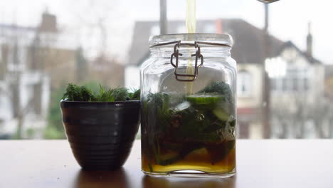 pouring hot liquid inside a jar filled with cucumber