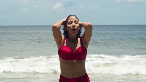 en el radiante sol, una joven con el cabello rizado adorna una playa de una isla tropical, vestida con un bikini rojo caminando por la playa