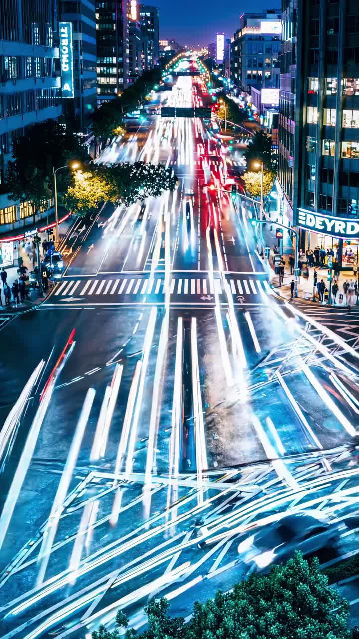 Aerial view of a bustling city intersection at night, with streaking lights creating a dynamic video
