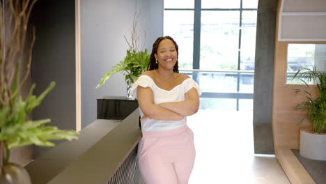 smiling woman standing with arms crossed in modern office lobby