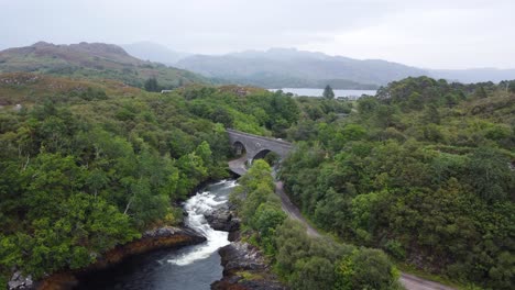 puente sobre la cascada del río morar, costa oeste de escocia - drone aéreo 4k hd inferior revelado