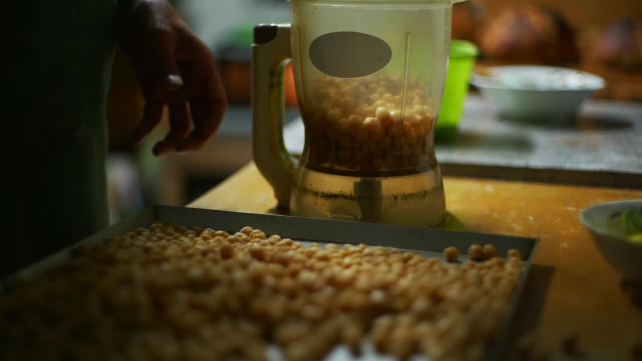 Chickpeas spooned out of baking tray and placed into blender, filmed as close up slow motion shot