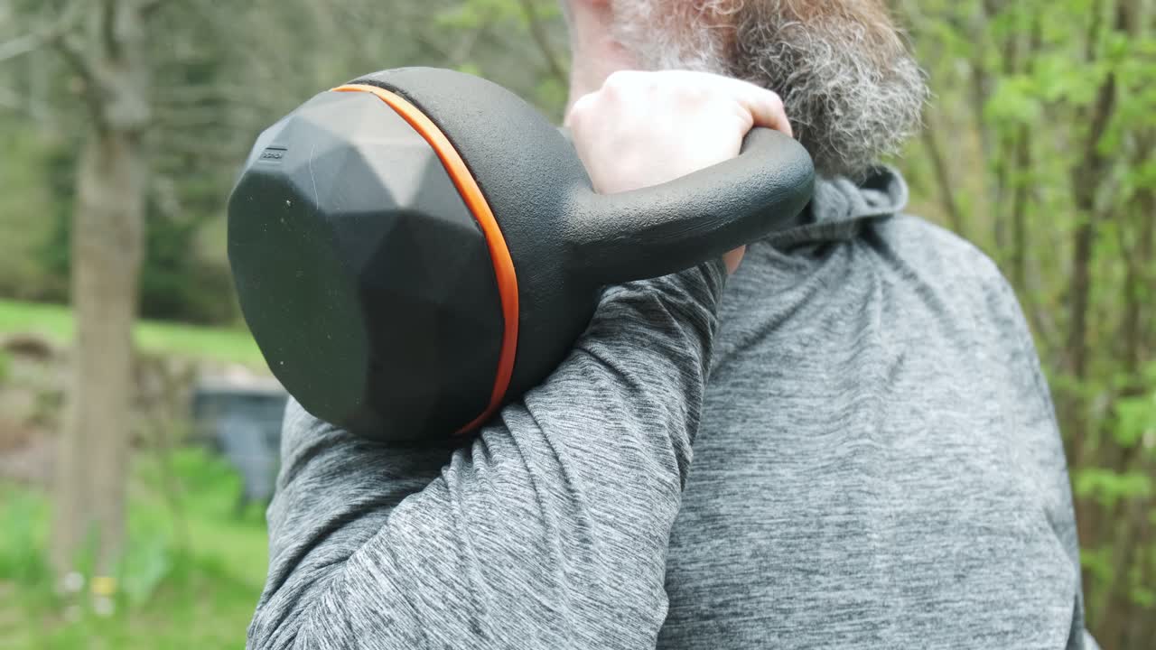 Close up of a man holding a 16 kg kettlebell in the rack position outside in slow motion 4K