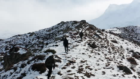 tres personas caminando hasta el campamento base de nanga parbat en pakistán - toma aérea de drones