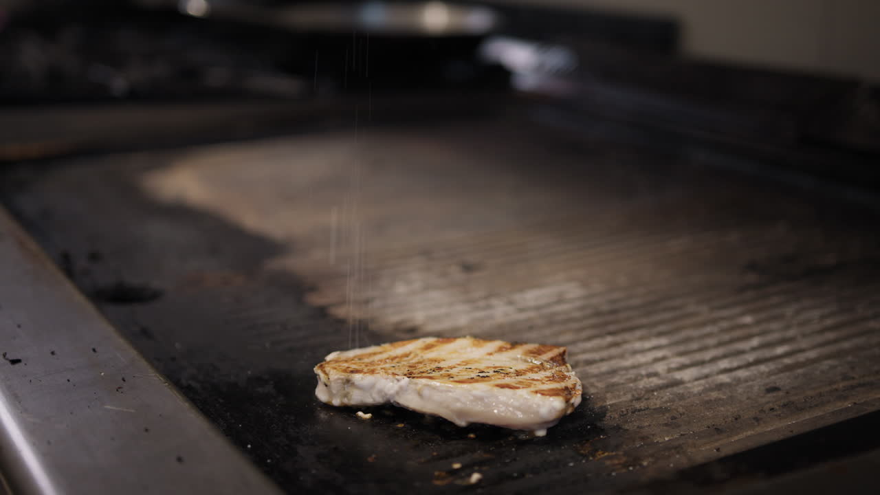 Salt Falling On Top Of The Swordfish Cooking On The Grill