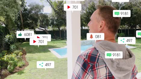 Animation-Von-Social-Media-Symbolen,-Die-über-Einem-Kaukasischen-Mann-Schweben,-Der-Auf-Der-Veranda-Des-Hauses-Steht