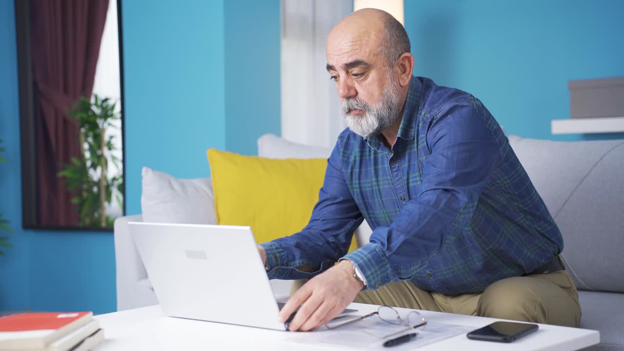 Old man having difficulty using laptop.