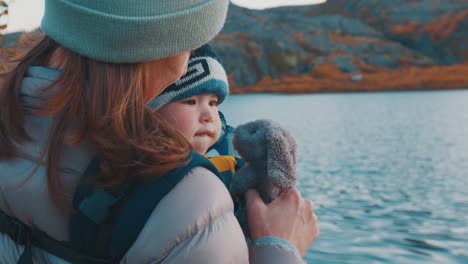 family hike in arctic. mother hikes with her toddler daughter in the arctic area and tries to entertain her with fluffy toy