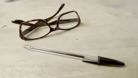 Reading-glasses-and-a-black-ball-point-pen-sitting-on-a-table-top