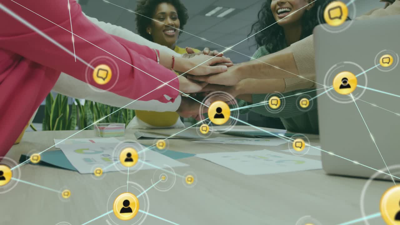 Animation of connected icons over diverse female coworkers stacking hands in office