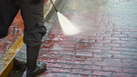 slow motion closeup of a person power washing brick or cobblestone street