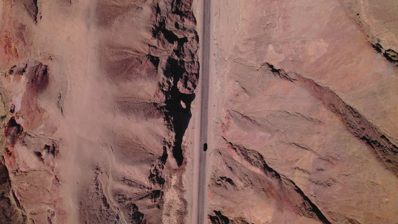 Aerial zenithal shot following a car driving through a desert highway in Peru