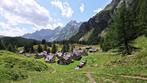 traditional alpine houses in crampiolo sit among meadows and peaks in alpe devero, piedmont, italy, under a sunny summer sky