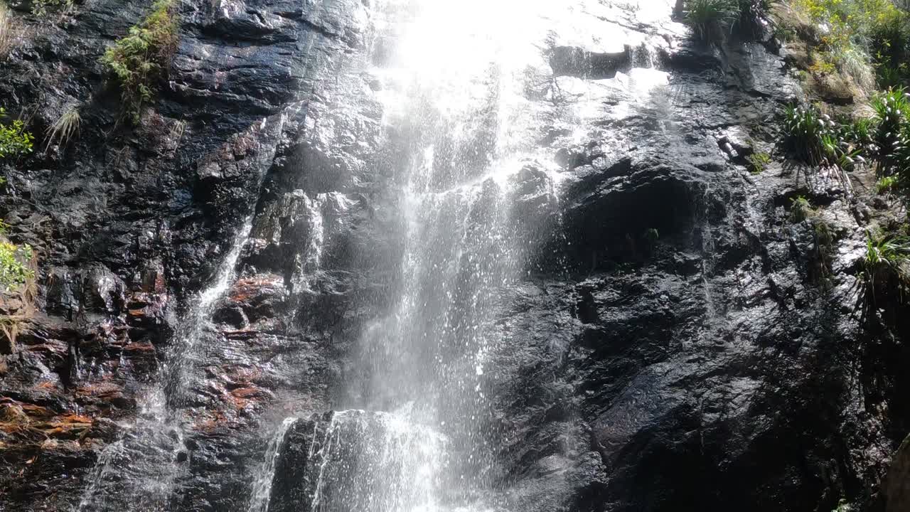 Foss som strømmer over steinete klippe i skog