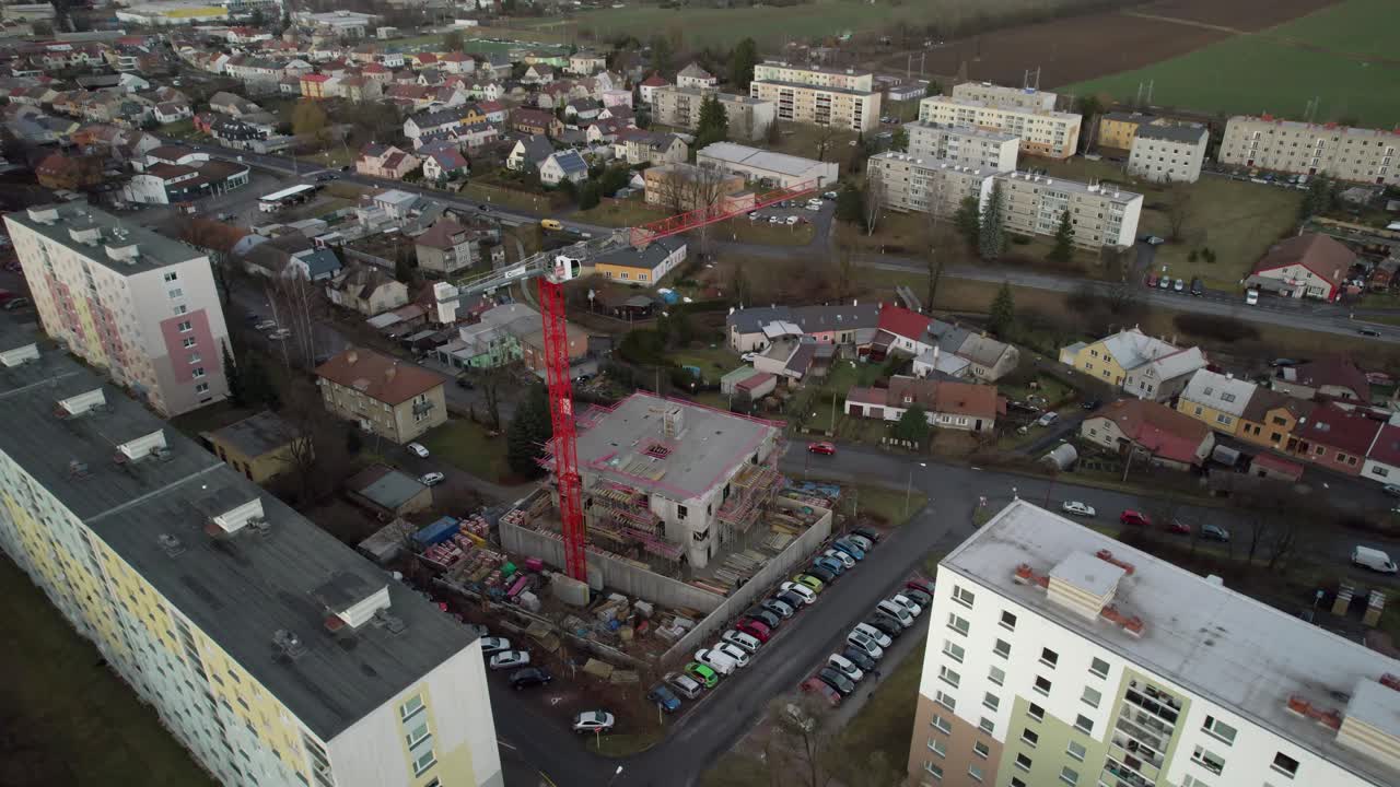 Tall red crane on the construction of a new house in the housing estate - view from the drone, moving forward