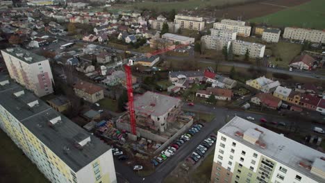 tall red crane on the construction of a new house in the housing estate - view from the drone, moving forward
