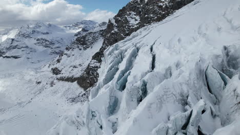 Vuelo-Aéreo-Sobre-La-Vista-De-Las-Grietas-De-La-Cara-De-Un-Gran-Glaciar-En-Un-Día-Soleado-En-Invierno-En-Los-Alpes