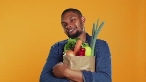 modelo masculino abrazando su bolsa de papel llena de comida orgánica de cultivo doméstico