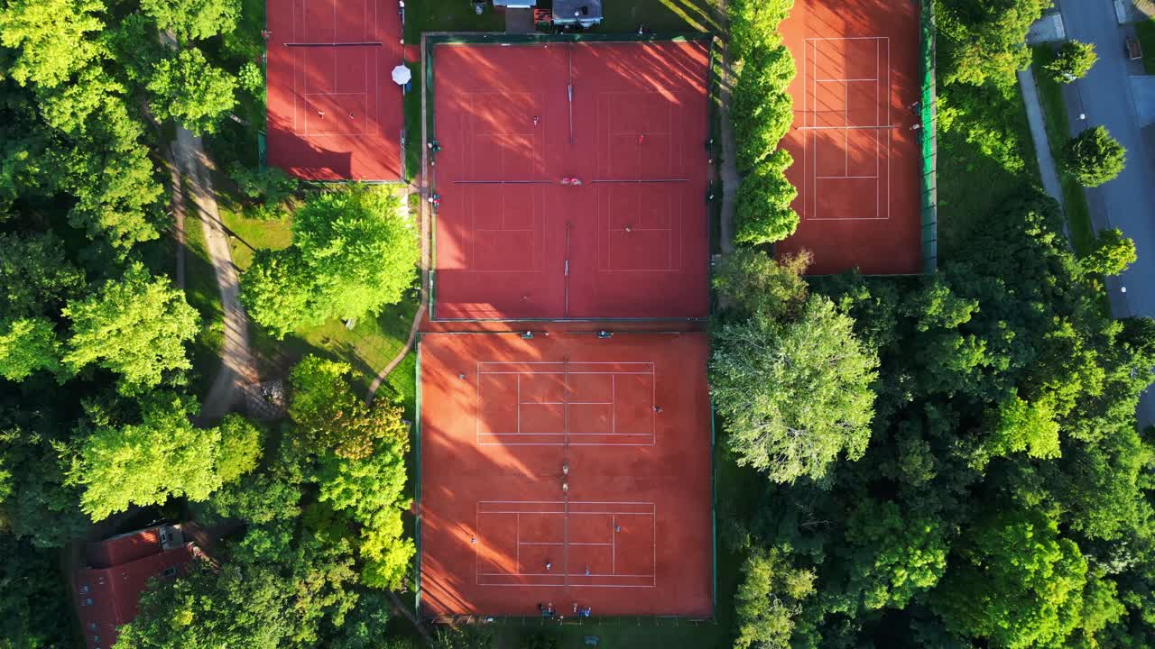 several tennis courts nestled within a dense forest, providing a tranquil escape in the heart of the city Berlin. Beautiful aerial view flight vertical bird's eye view overflight flyover drone