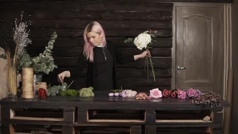 impressive front florist shooting at work. a nice girl collects flowers in a composition. indoors