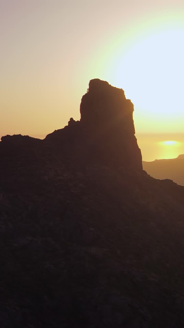Maestosa vista aerea del monolito Roque Bentayga stagliato contro un'alba dorata sulle montagne di Gran Canaria, Isole Canarie.