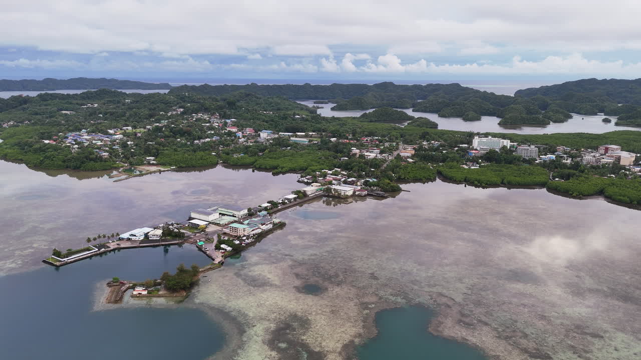 High-quality drone shot scanning and revealing the vivid aqua ocean and green-covered terrain in Palau. Circling drone shot of an island resort