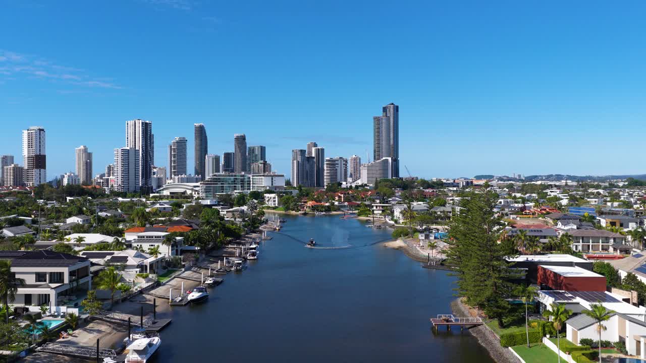 Drone footage captures Gold Coast's skyline and waterways under clear blue skies, showcasing urban architecture and natural beauty