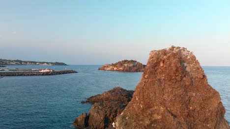 Aerial,-steep-rocky-islands-of-Sicily-east-coast-of-Aci-Trezza,-slide-right