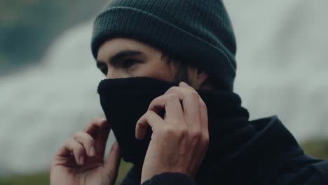 face of young man adjusting neck warmer in iceland