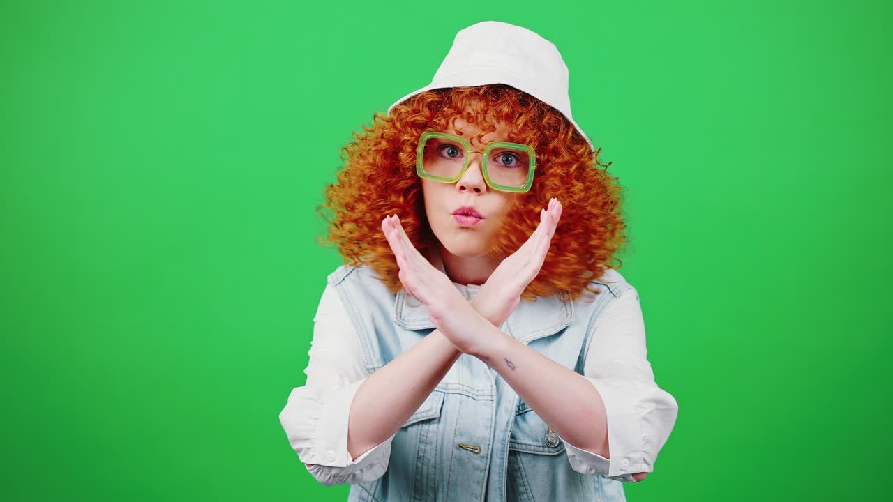Restriction concept. Studio portrait of young redhead curly woman saying NO and crossing hands, rejecting and denying